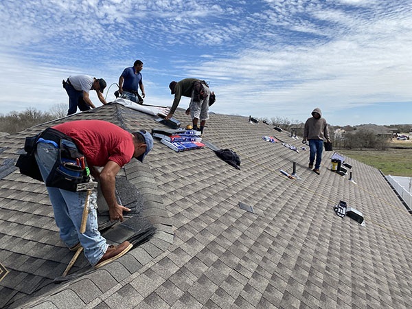 A group of roofers installing a grey roof in Austin, Texas.